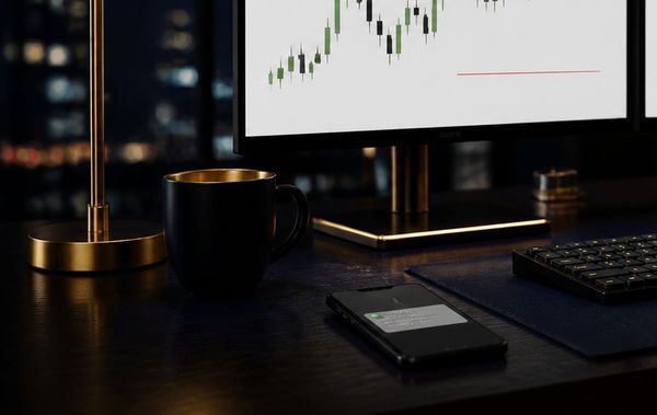 A desk with a phone showing a message notification, a mug and a brass lamp